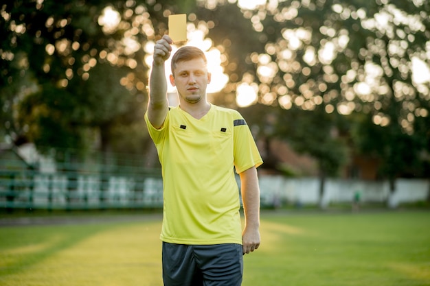 Árbitro de fútbol para señalar una tarjeta amarilla a un jugador en el estadio de fútbol