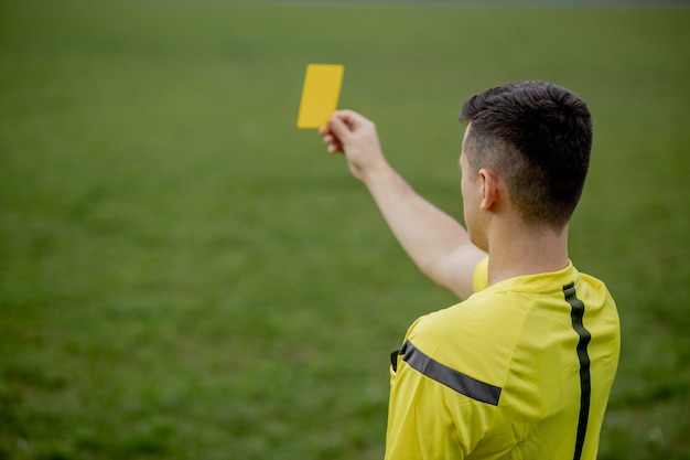 Árbitro que muestra una tarjeta roja a un jugador de fútbol o fútbol disgustado mientras juega. Concepto de deporte, violación de reglas, temas controvertidos, superación de obstáculos.