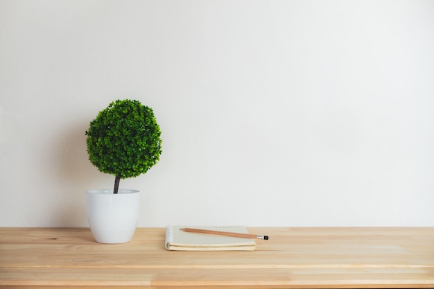 Árbol artificial con el cuaderno y el lápiz en el escritorio del trabajo.