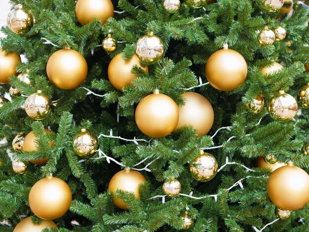 Árbol callejero decorado con bolas doradas. Foto de alta calidad