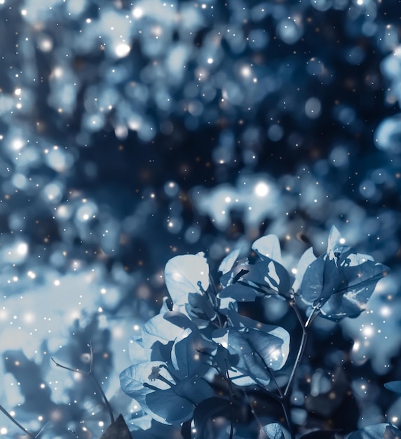 Árbol floreciente de fondo floral azul y flores con nieve y brillo para las vacaciones