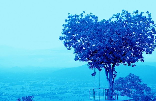 Árbol en forma de corazón de estilo surrealista de arte pop en cielo nublado en tono de color azul vibrante