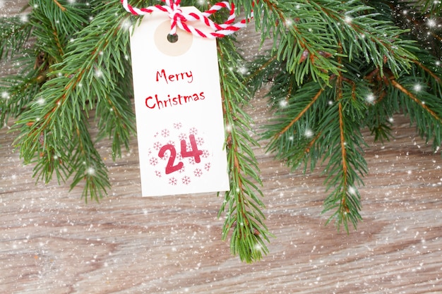Árbol de hoja perenne con etiqueta de feliz navidad para el 24 de diciembre