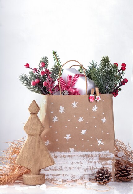 Árbol de madera decorativo navideño y bolsa de papel para regalos, ramas de abeto y conos