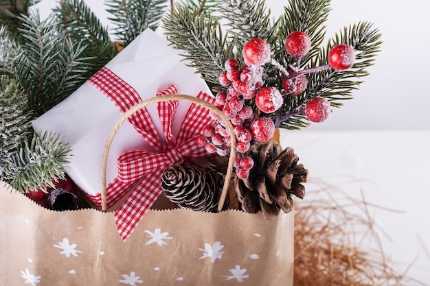 Árbol de madera decorativo navideño y bolsa de papel para regalos, ramas de abeto y conos