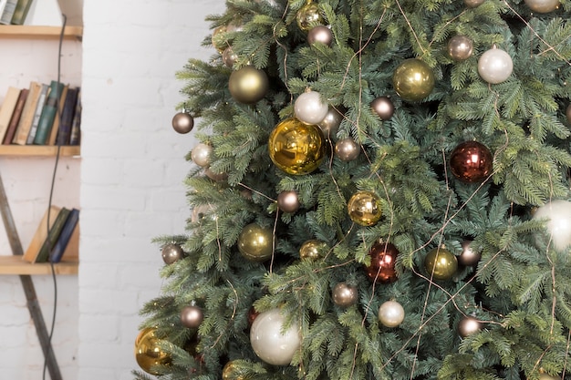 Árbol de Navidad con adornos blancos, dorados y bronce brillantes en la sala de estar