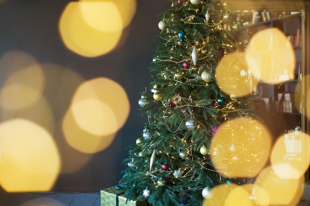 Árbol de navidad con adornos dorados y luces en un interior oscuro