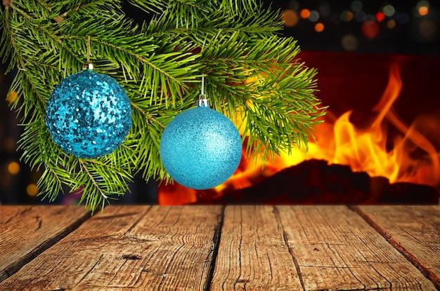 Árbol de navidad con adornos en una mesa de madera contra una chimenea en el fondo