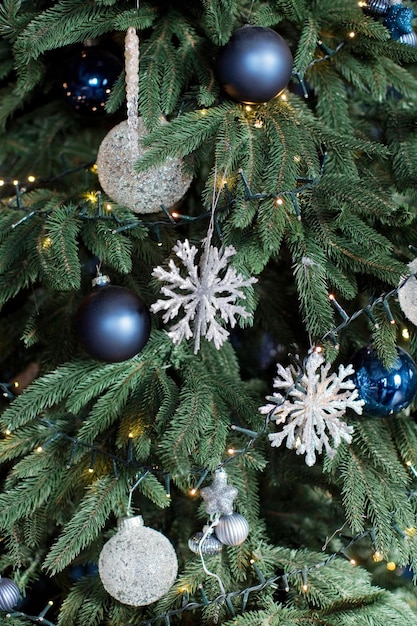 Árbol de navidad con adornos plateados y azules y guirnalda de luces navideñas