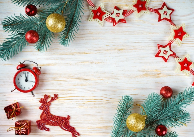 Árbol de Navidad y año nuevo decorado, ciervos de juguete, guirnaldas y reloj sobre fondo blanco de madera con espacio de copia. Vista superior, piso plano.