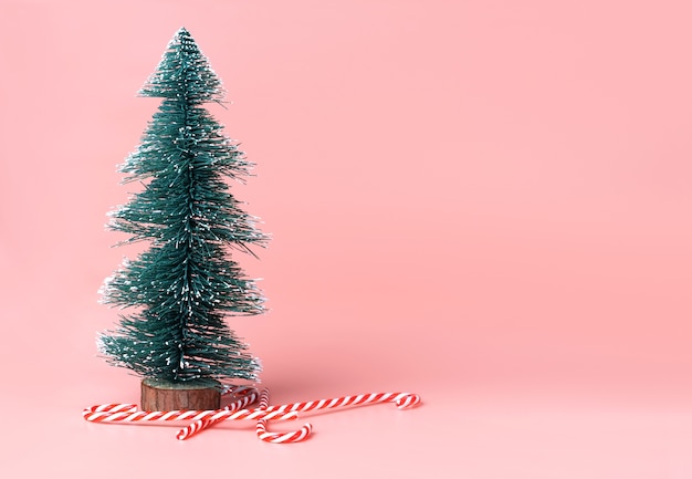 Árbol de navidad con el bastón de caramelo en fondo rosado en colores pastel del estudio