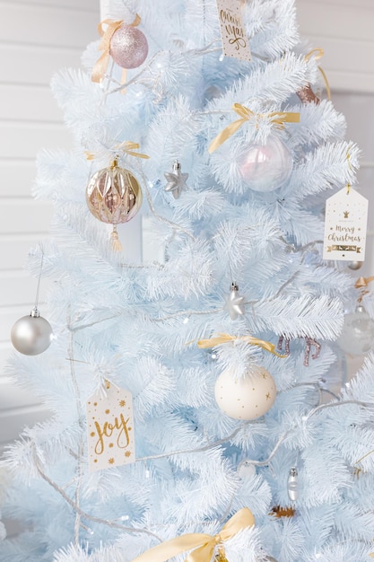 Árbol de Navidad blanco decorado con bolas de Navidad de color rosa dorado plateado y hermosas bolas de cristal en la rama azul blanca brillante y de hadas, luces decorativas, espacio de copia. Foto.