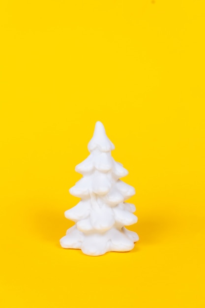 Árbol de Navidad blanco sobre fondo amarillo vivo.