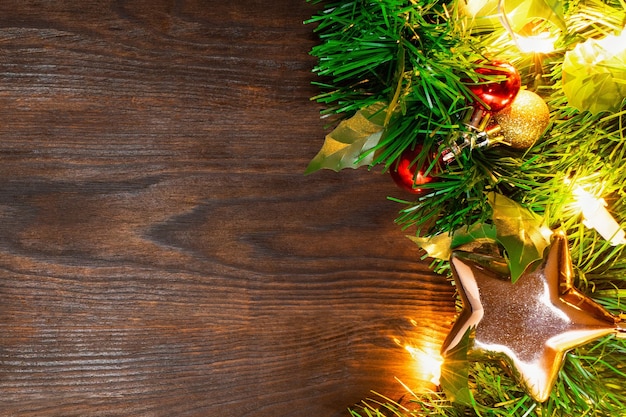 Árbol de Navidad con bolas, estrella dorada y guirnalda de luces amarillas se encuentran en la mesa de madera de color marrón oscuro