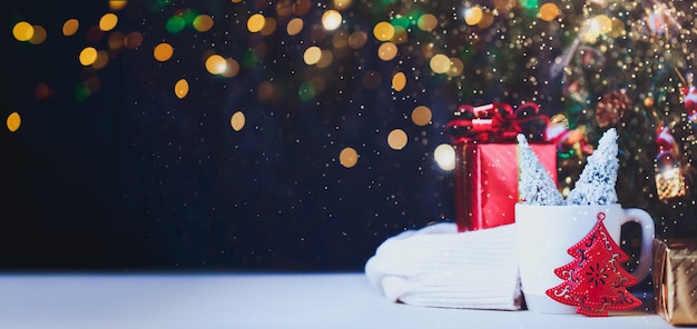 Árbol de Navidad y caja de regalo en taza con fondo claro del festival bokeh