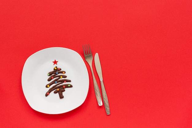 Árbol de Navidad de chocolate dulce en plato y cubiertos