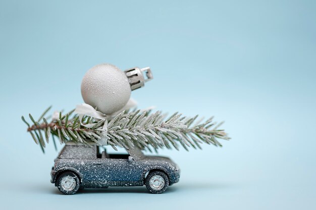 Árbol de Navidad en un coche de juguete sobre un fondo azul.