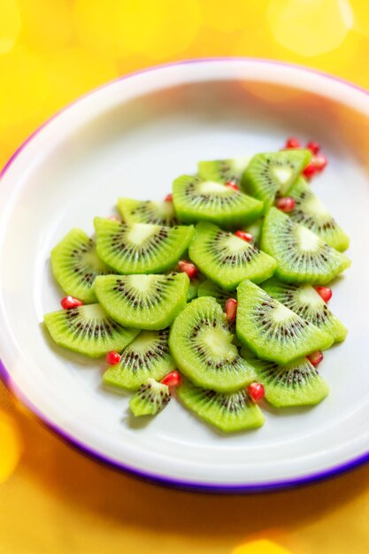 Árbol de Navidad comestible hecho de kiwi y granada sobre mantel amarillo