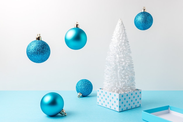 Árbol de Navidad cubierto de nieve con decoración navideña en mesa azul