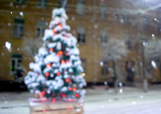 Árbol de Navidad cubierto de nieve que brilla intensamente luces de colores durante las nevadas al aire libre