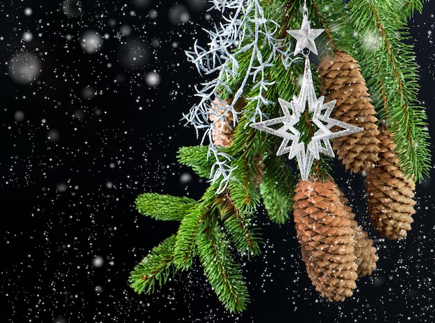 Árbol de Navidad con decoración plateada brillante sobre fondo negro con efecto de nieve cayendo