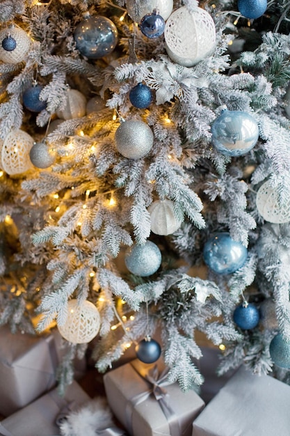 Árbol de navidad con decoraciones y luces plateadas y azules Acogedor árbol de navidad y fondo de cajas de regalo