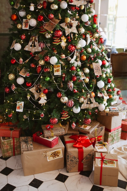 Árbol de Navidad decorado con adornos navideños y regalos.