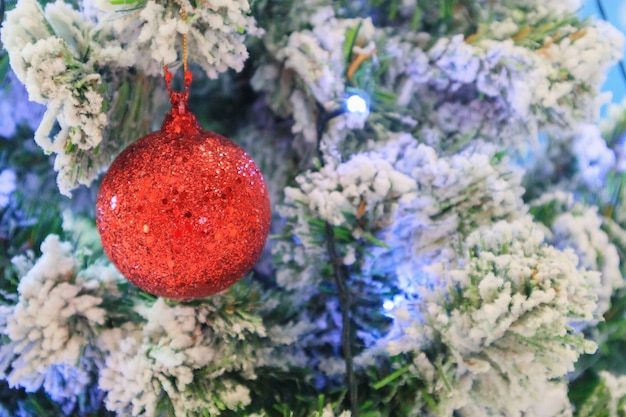 Árbol de Navidad decorado con bola roja sobre fondo de ramas de pino