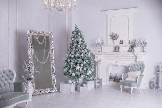 Árbol de Navidad decorado y cajas de regalo en la sala de estarGran salón blanco muebles antiguos