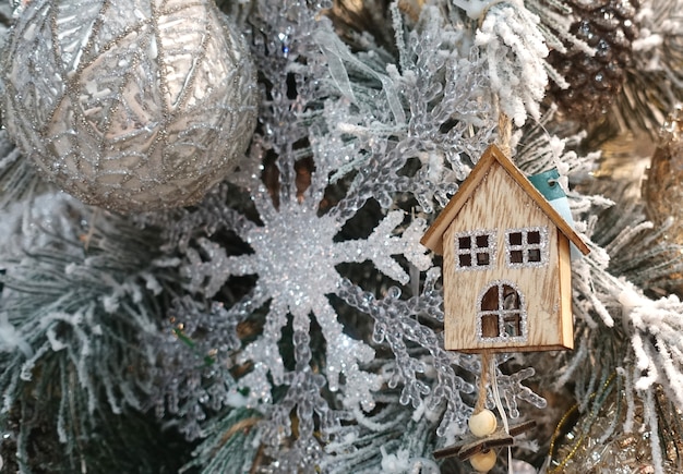 Árbol de Navidad decorado con copos de nieve y casa de madera.