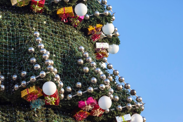 Árbol de Navidad decorado en el fondo de cielo azul. Parte del gran primer plano del árbol de Navidad al aire libre