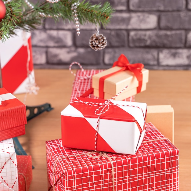 Árbol de Navidad decorado con hermosos regalos envueltos en rojo y blanco en casa con pared de ladrillo negro, concepto de diseño festivo, de cerca.