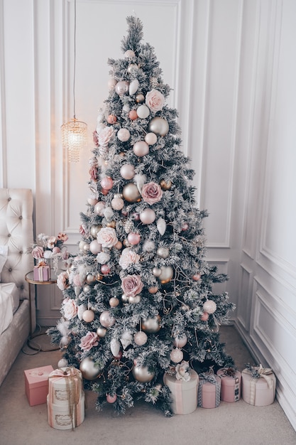 Árbol de Navidad decorado en interior de dormitorio clásico blanco con ramo de vacaciones de Año Nuevo en un jarrón