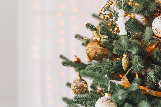 Árbol de Navidad decorado con juguetes dorados y blancos con el fondo texturizado bokeh de luces