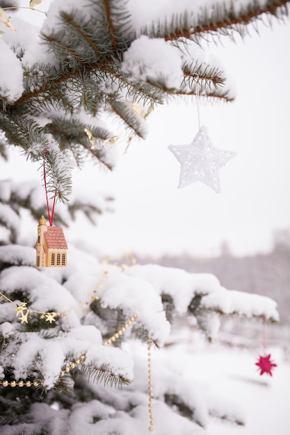 Árbol de navidad decorado con juguetes rojos y dorados al aire libre y cubierto de nieve