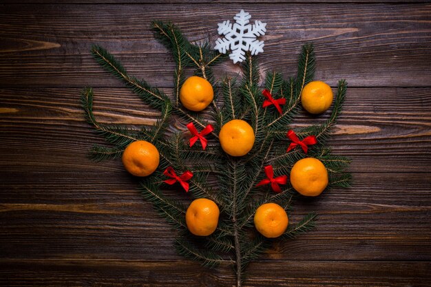 Árbol de Navidad decorado con mandarinas y regalos de bolas sobre un fondo de madera