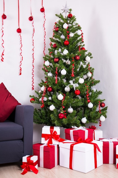 Árbol de Navidad decorado y montón de regalos en el salón