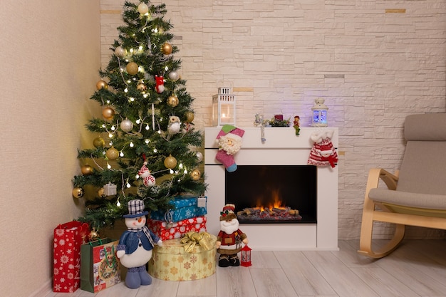 Árbol de Navidad decorado, regalos y adornos navideños cerca de la chimenea encendida
