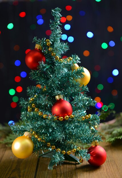 Árbol de Navidad decorativo en mesa sobre fondo brillante