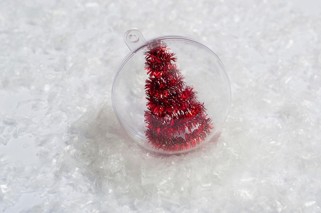 Árbol de Navidad dentro de una bola transparente en la nieve. Concepto mínimo de postal, tarjeta de invitación. Cerrar con espacio de copia