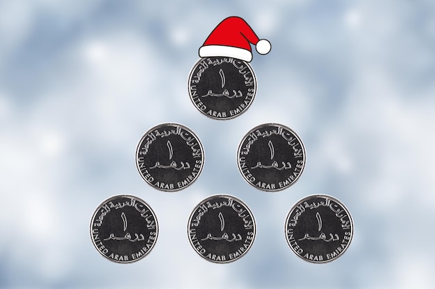 Árbol de Navidad Emiratos Árabes Unidos Las monedas de un dirham se apilan en forma de pirámide y una gorra de Papá Noel en un fondo borroso del Año Nuevo