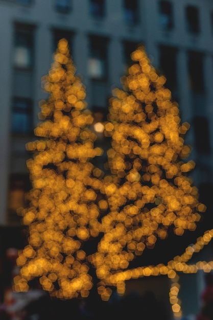 Árbol de navidad en guirnalda de luces de navidad en el fondo del edificio de varios pisos imagen borrosa pared de la pared...