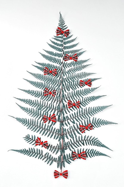 Árbol de Navidad hecho de arcos de cinta decorativa de hojas de helecho natural sobre fondo blanco, endecha plana