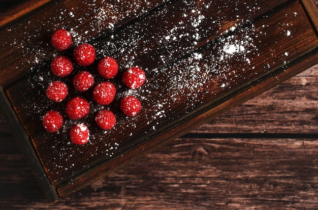 Árbol de Navidad hecho de frambuesas rojas con azúcar en polvo sobre un fondo de madera