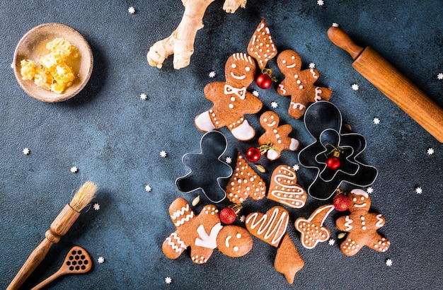 Árbol de Navidad hecho de galletas de jengibre sobre fondo azul oscuro con espacio para copiar texto. Galleta de jengibre con utensilios de cocina. postal de navidad y año nuevo. Galletas surtidas.