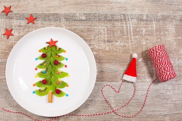 Árbol de Navidad hecho de rodajas de kiwi en placa