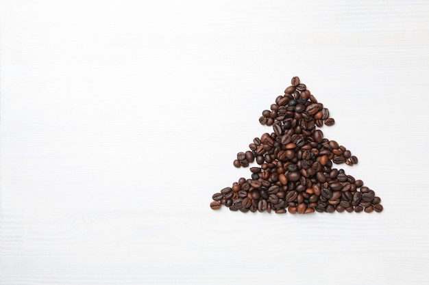 Árbol de navidad hecho de semillas de café en un espacio de fondo blanco de madera para texto