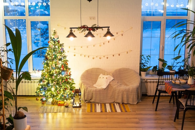 Árbol de Navidad en el interior blanco de una casa con paredes de ladrillo estilo loft con guirnaldas de juguetes de vidrio en una cuerda Luces brillantes decoración de la sala de estudio Acogedor hogar en Navidad y año nuevo