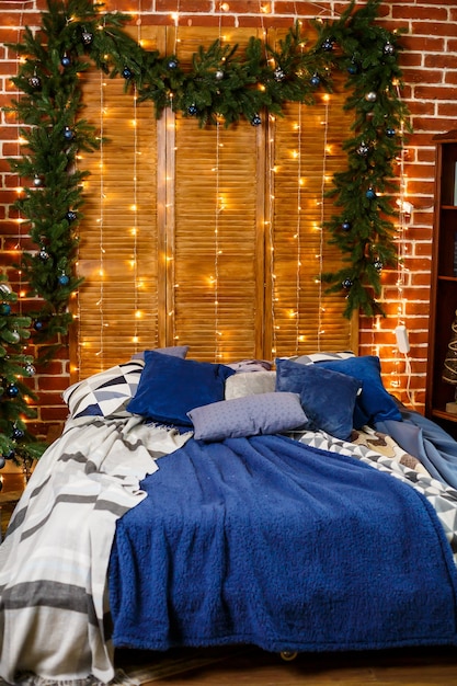 Árbol de Navidad con juguetes azules en el dormitorio. Casa bellamente decorada para el año nuevo con adornos para árboles y camas