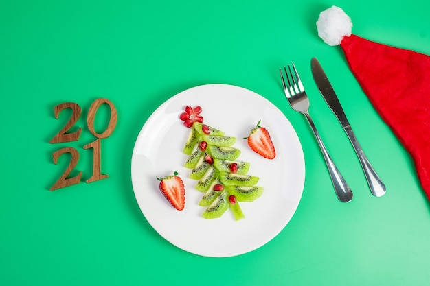 Árbol de navidad de kiwi y granada con tenedor y cuchillo